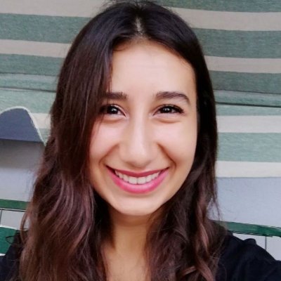Uzun kahverengi saçlı kırmızı-pembe tonlu rujlu bir kadın gülümsüyor. Fotoğraf sadece yüzünü ve saçlarını gösteriyor